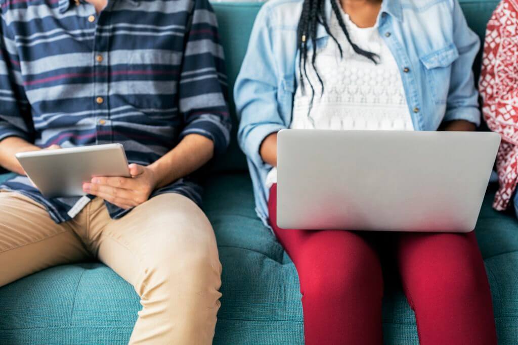 couple on couch with tablet and laptop