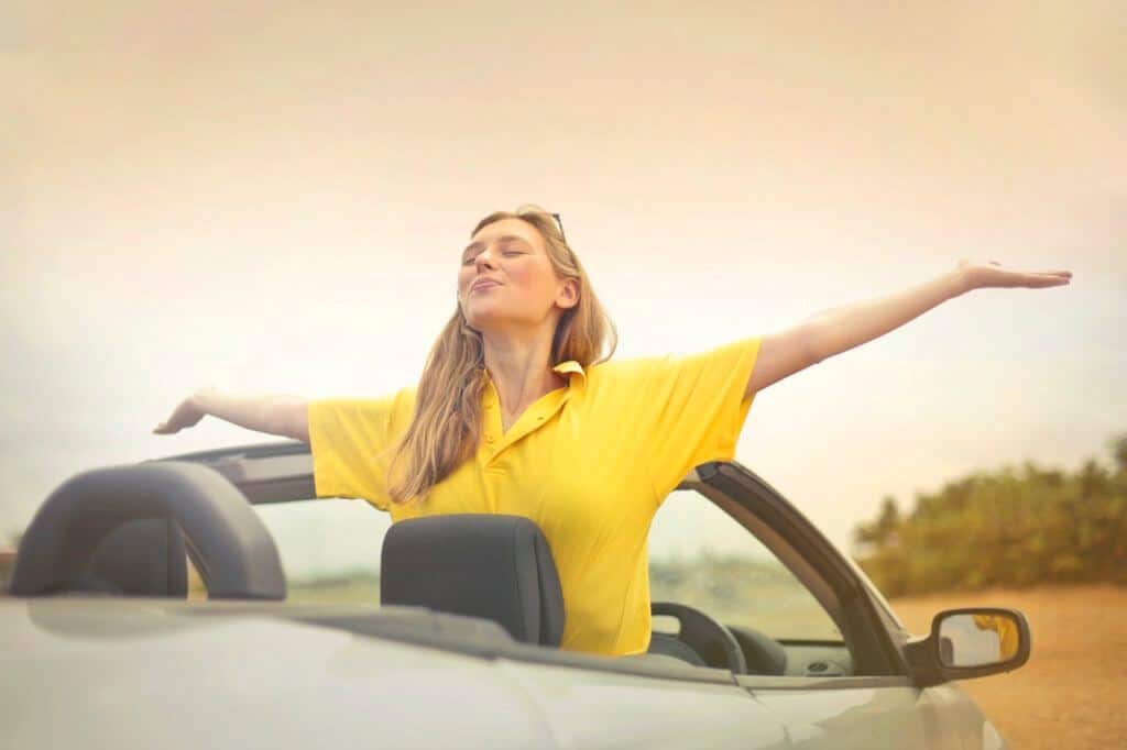 woman standing in parked convertible