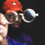 man in read cap and beard holding glasses