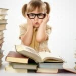 Young girl in glasses between stack of books