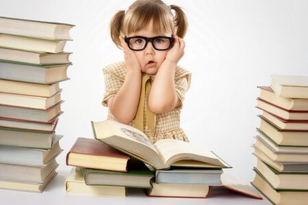 Little girl surrounded by books wearing black glasses back to school concept isolated over white
