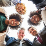 Friends in huddle smiling down at camera