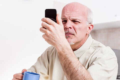 Older man holding phone close to eyes