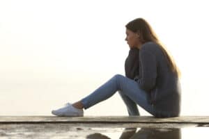 woman sitting on ledge with sun in the background