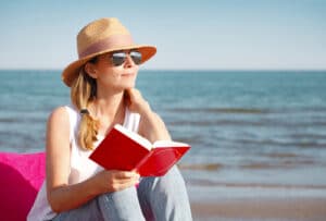 woman reading book on beach during Cataract Awareness Month