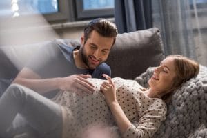 A man smiling and touching a pregnant woman's stomach