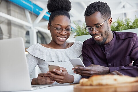 Young couple with glasses on laptop and phones