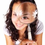 young woman looking through magnifying glass