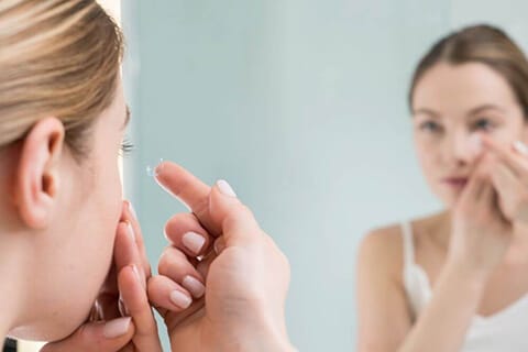 Young woman putting in contact lens
